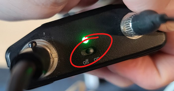 Microphone transmitter with on/off switch at top of device circled